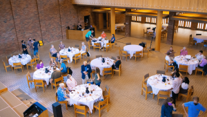 View from above of the Chapel of the Learning Event #4 of round tables with people sitting and standing around them.